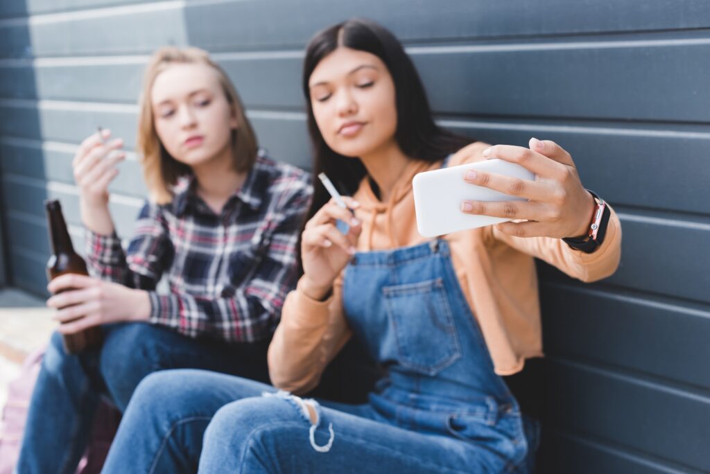 Two teenage girls smoking cigarettes and taking a selfie