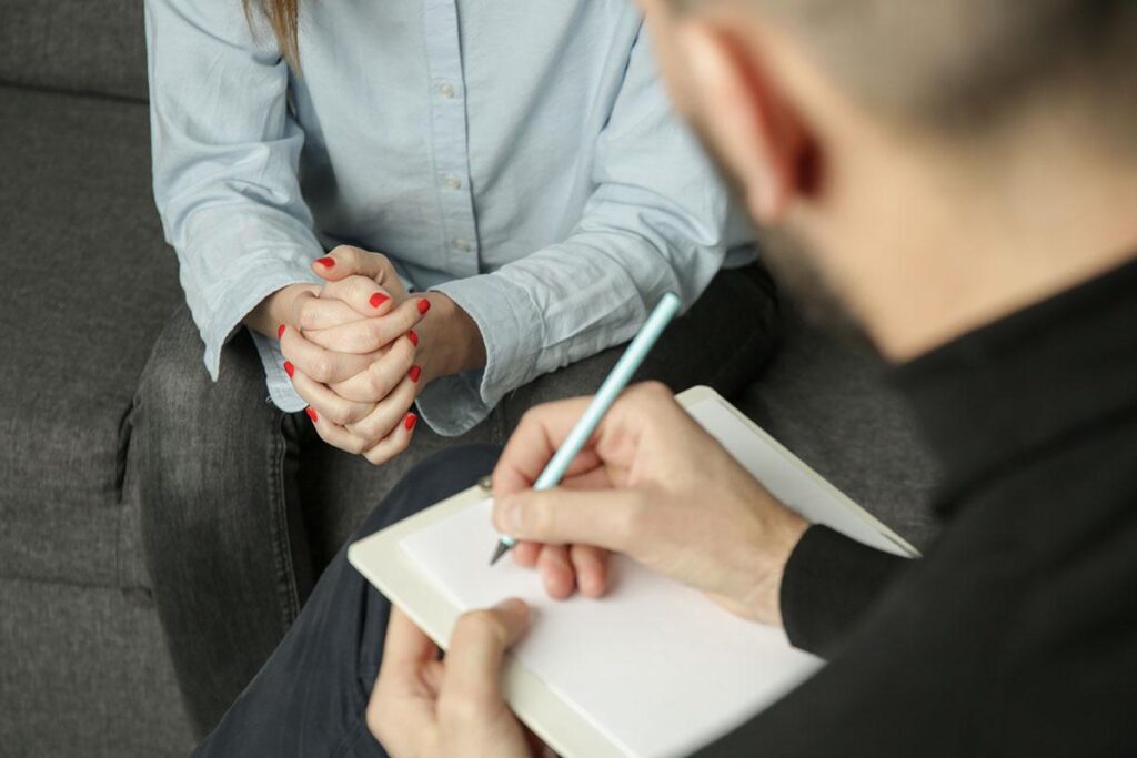 One person taking notes in a notebook while another one speaks