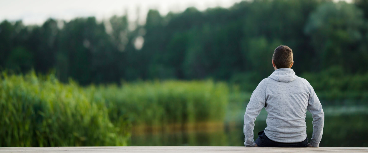 Man look at a pond in deep thought.