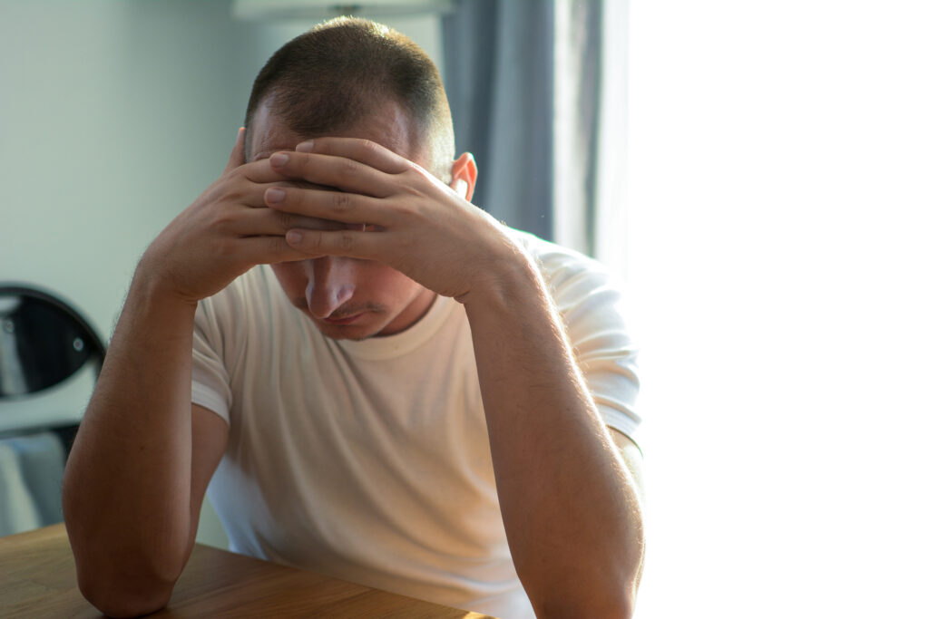 Man sitting at table holding head in hands